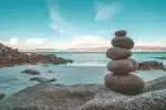 A scenic ocean view with a subject of a stacked stone in the shore.